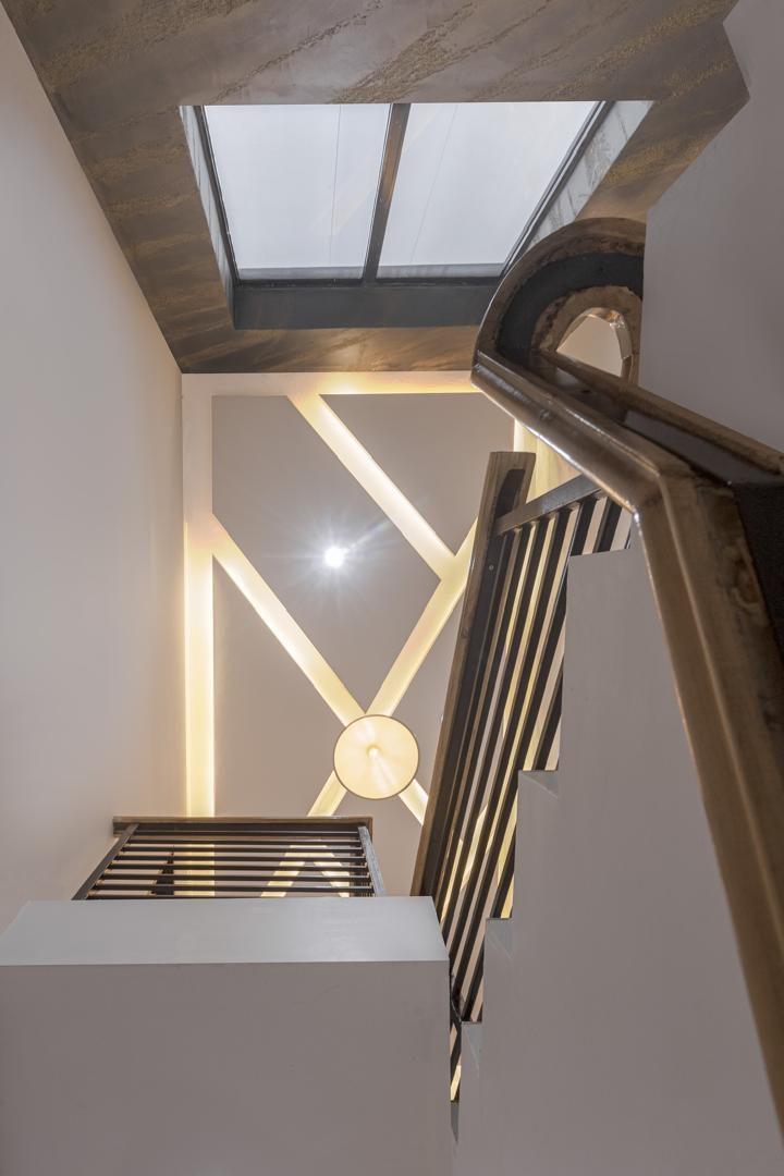 Staircase void with a skylight, curved timber handrail, slatted balustrade and geometric wall lighting